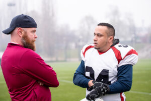 Sports Psychologist talking to football player on the field.