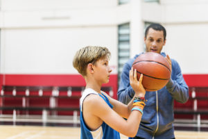 Sports psychologist working with a child on a basketball court